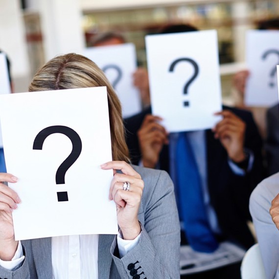People holding papers with question marks covering their faces.