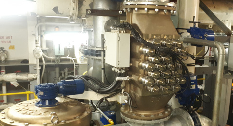 Industrial machinery with control panels and wiring, featuring DESMI equipment, in a facility.