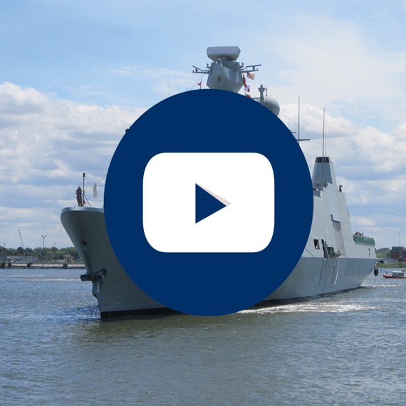 Warship in harbor with overlayed play button icon.