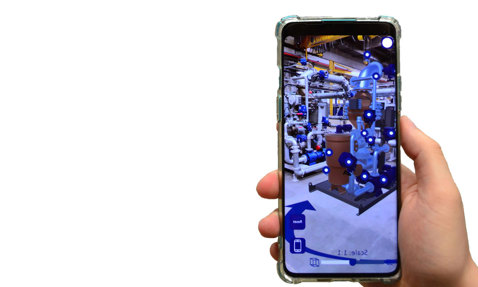Hand holding smartphone displaying augmented reality industrial equipment visualization.