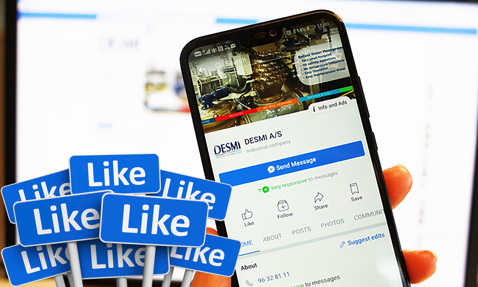 Smartphone displaying DESMI A/S Facebook page with multiple "Like" icons in foreground.