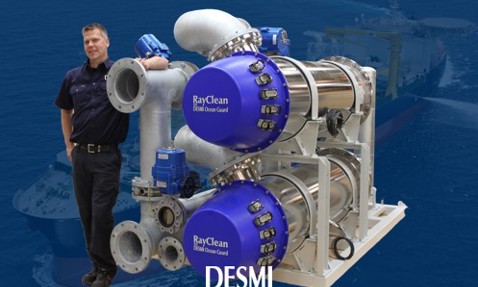 DESMI RayClean ballast water treatment system with a person standing beside it.