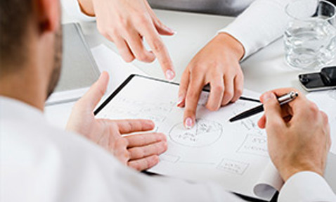 People discussing a diagram on a clipboard during a meeting.