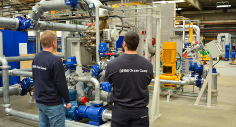 Two technicians inspect DESMI fluid handling equipment in an industrial facility.