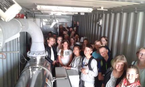 Group of people inside an industrial container with machinery visible.