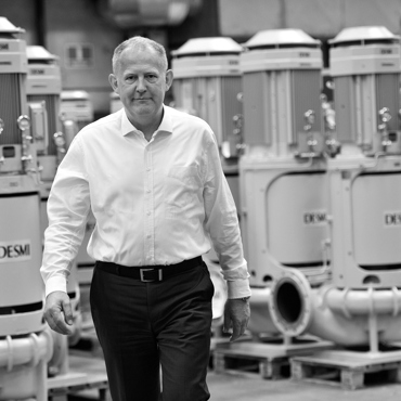 Man walking in a factory with DESMI pumps in the background.