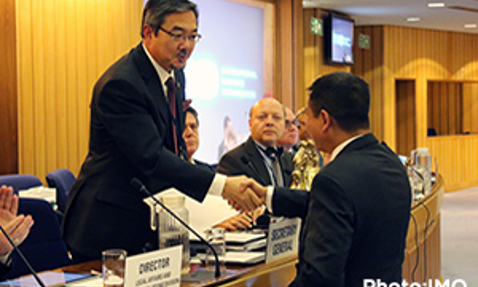 Two men shaking hands at a conference, with attendees in the background.