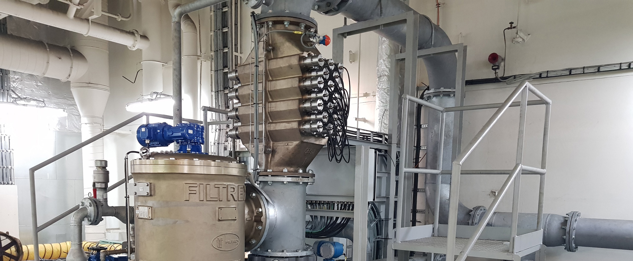 Industrial filtration system with metallic pipes and equipment in a facility.