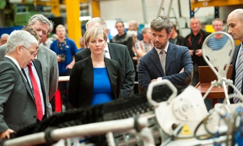 Group of people observing machinery in an industrial facility.