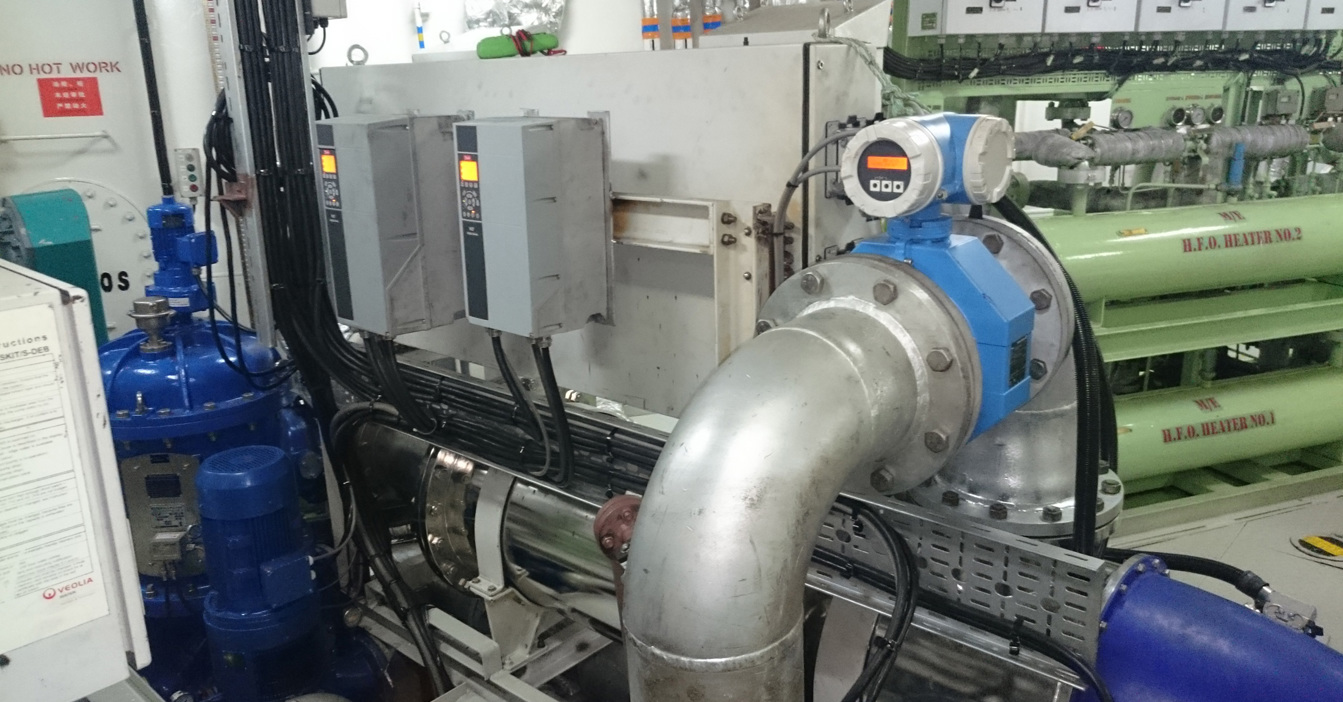 Industrial machinery setup featuring piping, control panels, and H.F.O. heaters in a facility.