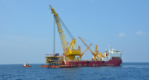 Large offshore construction vessel with cranes operating in open sea.