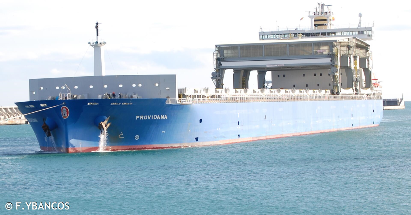 Blue cargo ship "Providana" sailing in calm waters near a breakwater.